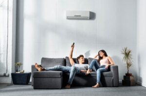 two-people-on-sofa-changing-temperature-of-mini-split-with-remote