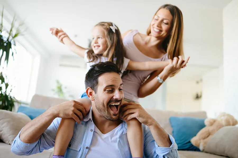 A young family playing in their living room, enjoying their climate controlled home.