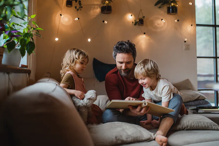 Young family reading a story on the couch in their living room, enjoying the warm indoors.