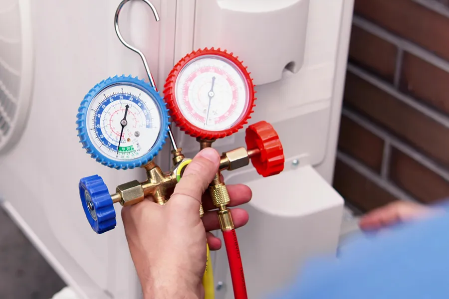 An HVAC technician servicing an inverter AC unit, measure the coolant levels with a gauge.
