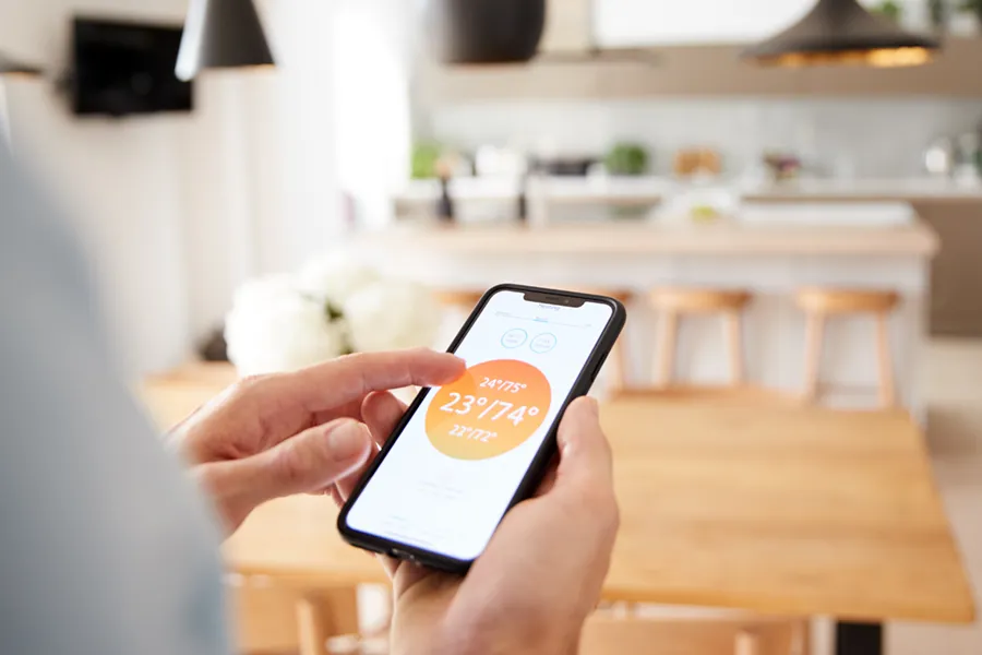 A person using a smartphone app to adjust the temperature on their smart thermostat.