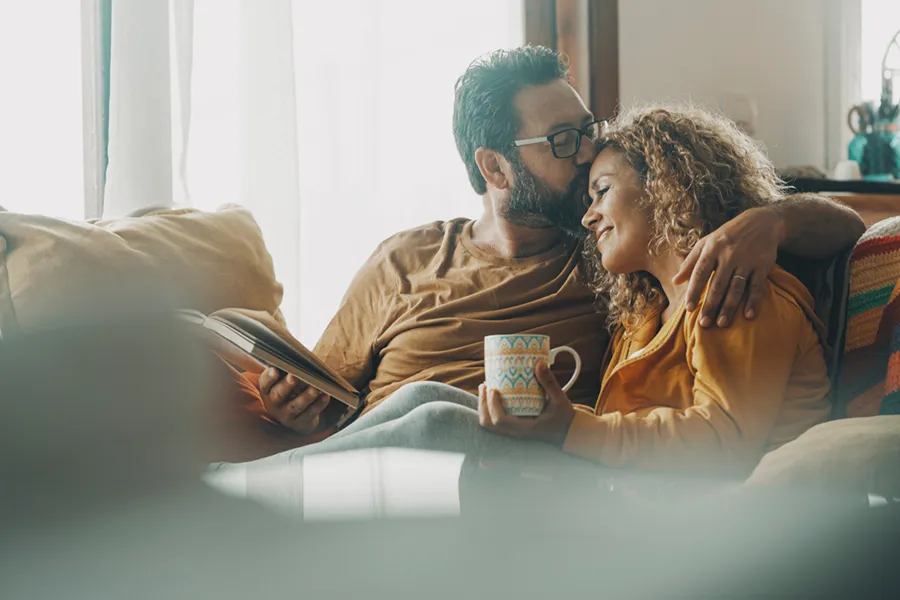 A young couple cuddling on the couch in their living room, enjoying their well-maintained climate control.