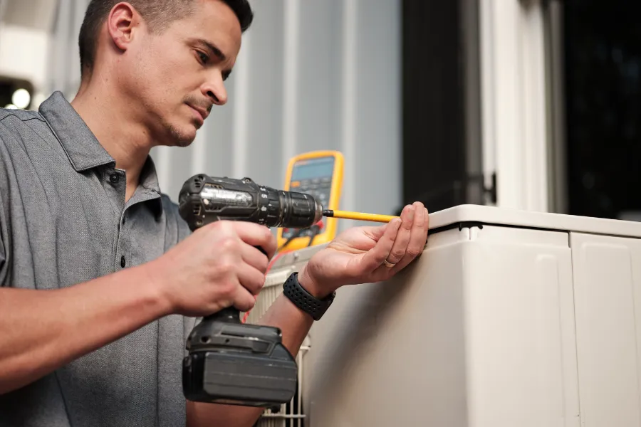 HVAC Install Technician using power tool on outdoor equipment