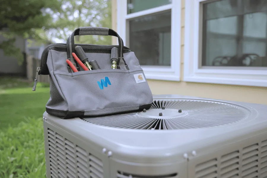 Tool bag sitting on top of an air conditioner